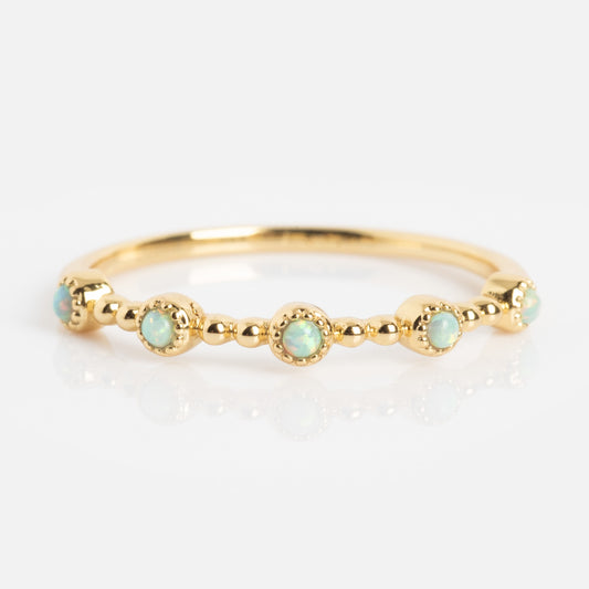 The Bezeled Beauty Stacking Ring showcases small, round opals set in decorative gold bezels evenly spaced around the band, accented with tiny gold beads for a delicate, elegant look.