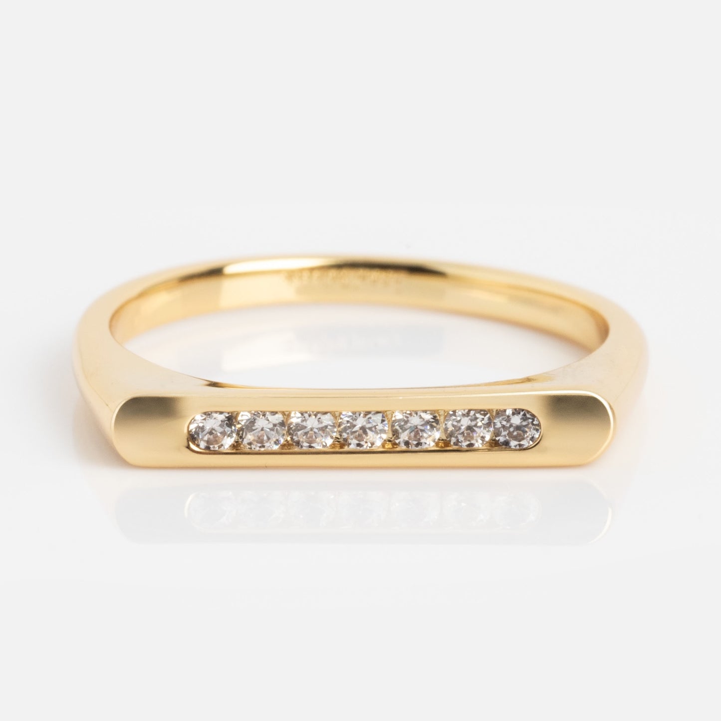 The Pave Bar Pinky Ring is a gold ring with a flat top, featuring a row of seven small round diamonds set in a straight line across the front.