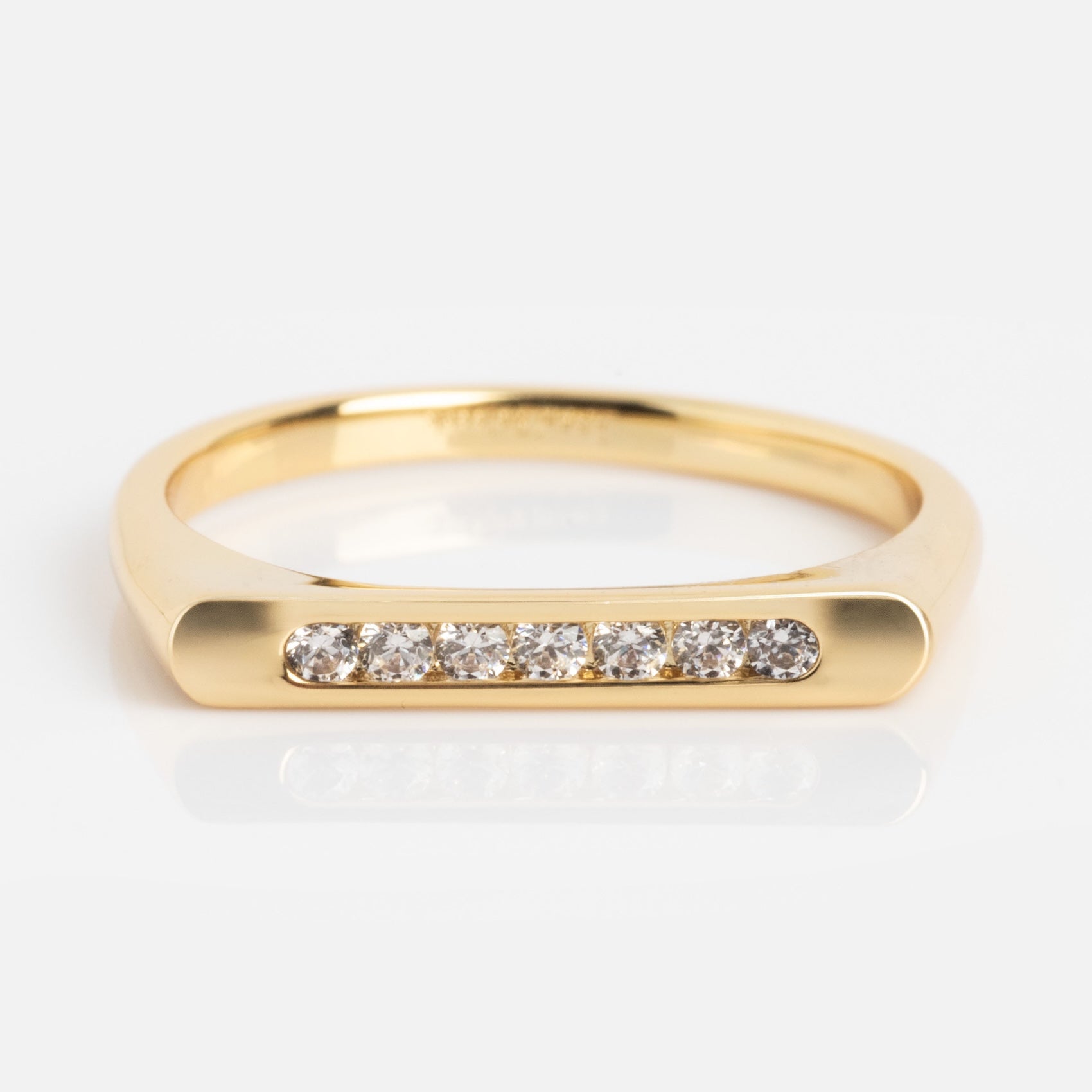 The Pave Bar Pinky Ring is a gold ring with a flat top, featuring a row of seven small round diamonds set in a straight line across the front.