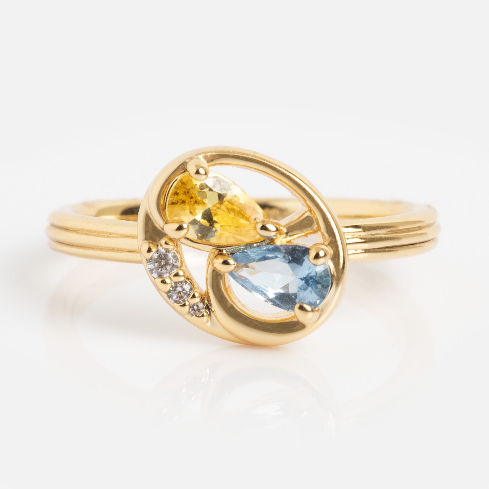 Eclectic Swirl Pinky Ring featuring teardrop-shaped yellow and light blue stones, plus three small round clear stones in an elegant swirl design, displayed against a white background.