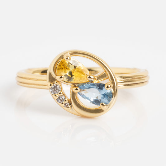 Eclectic Swirl Pinky Ring featuring teardrop-shaped yellow and light blue stones, plus three small round clear stones in an elegant swirl design, displayed against a white background.