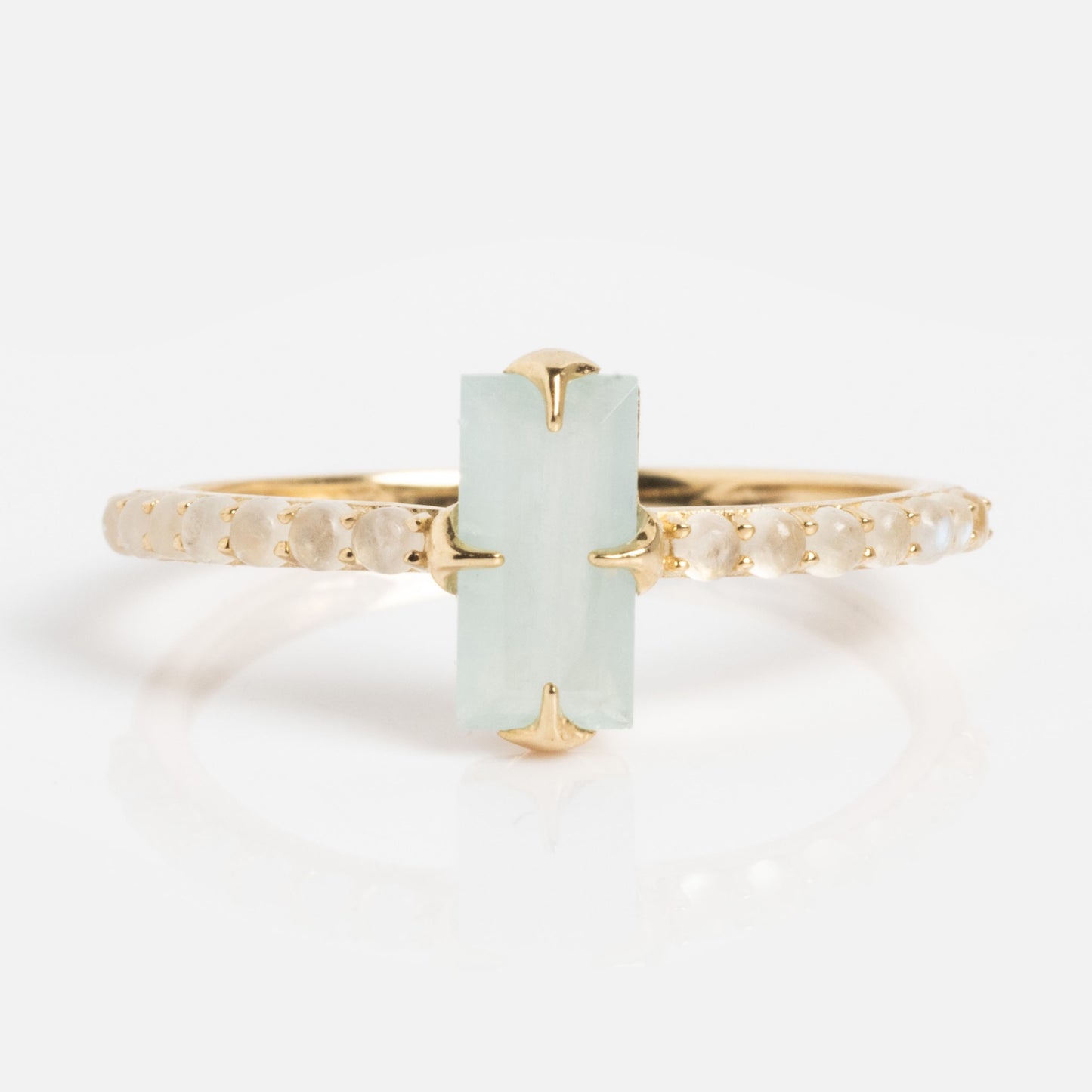 The 2026 March Capsule Delicate Aquamarine Solitaire Ring is a gold band featuring a rectangular pale green aquamarine gemstone in the center, held by four prongs, with small round diamonds set along the band.
