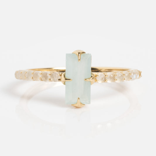 The 2026 March Capsule Delicate Aquamarine Solitaire Ring is a gold band featuring a rectangular pale green aquamarine gemstone in the center, held by four prongs, with small round diamonds set along the band.
