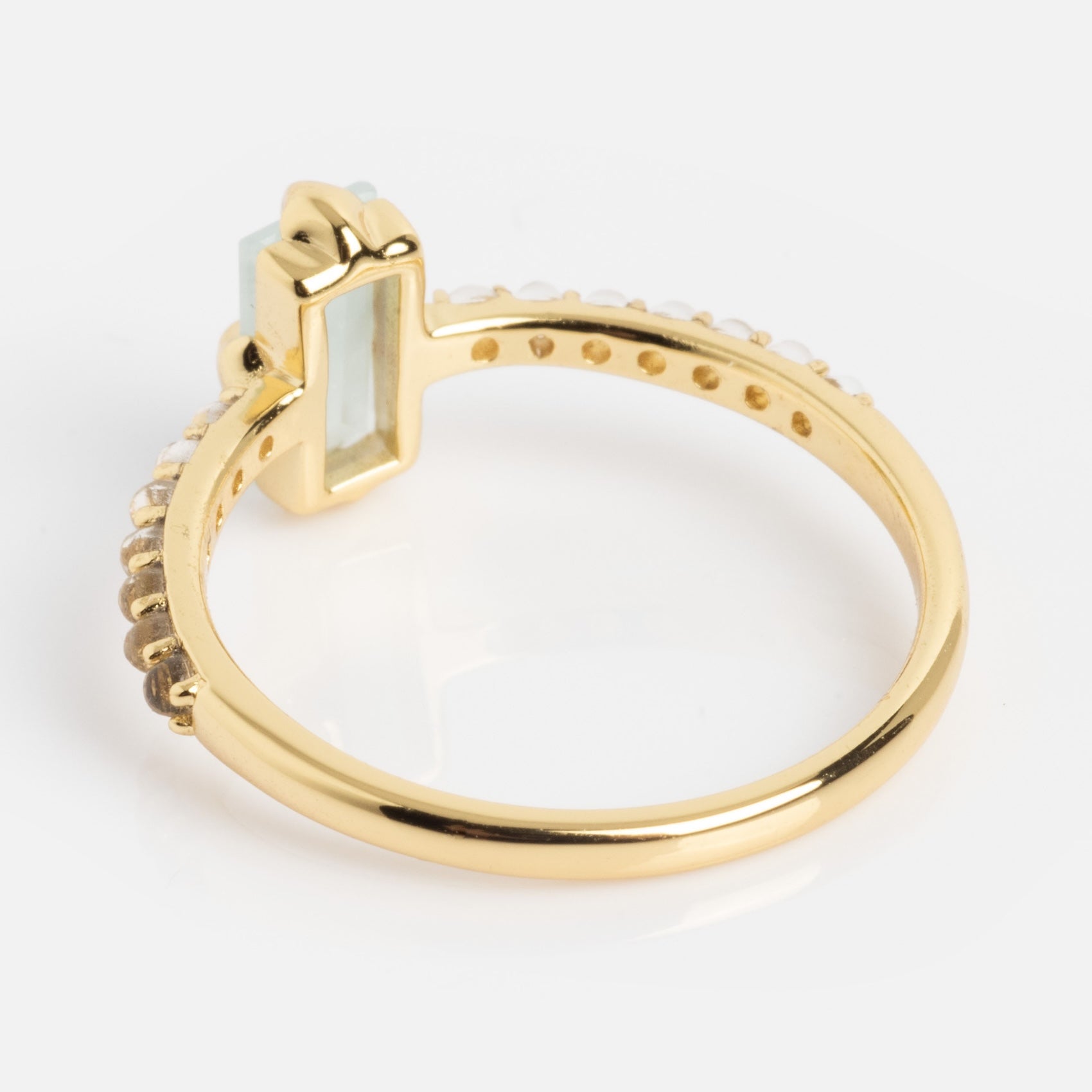 The 2026 March Capsule Delicate Aquamarine Solitaire Ring features a rectangular light blue aquamarine in a prong setting, accented by small round diamonds along the gold band, shown on a white background.