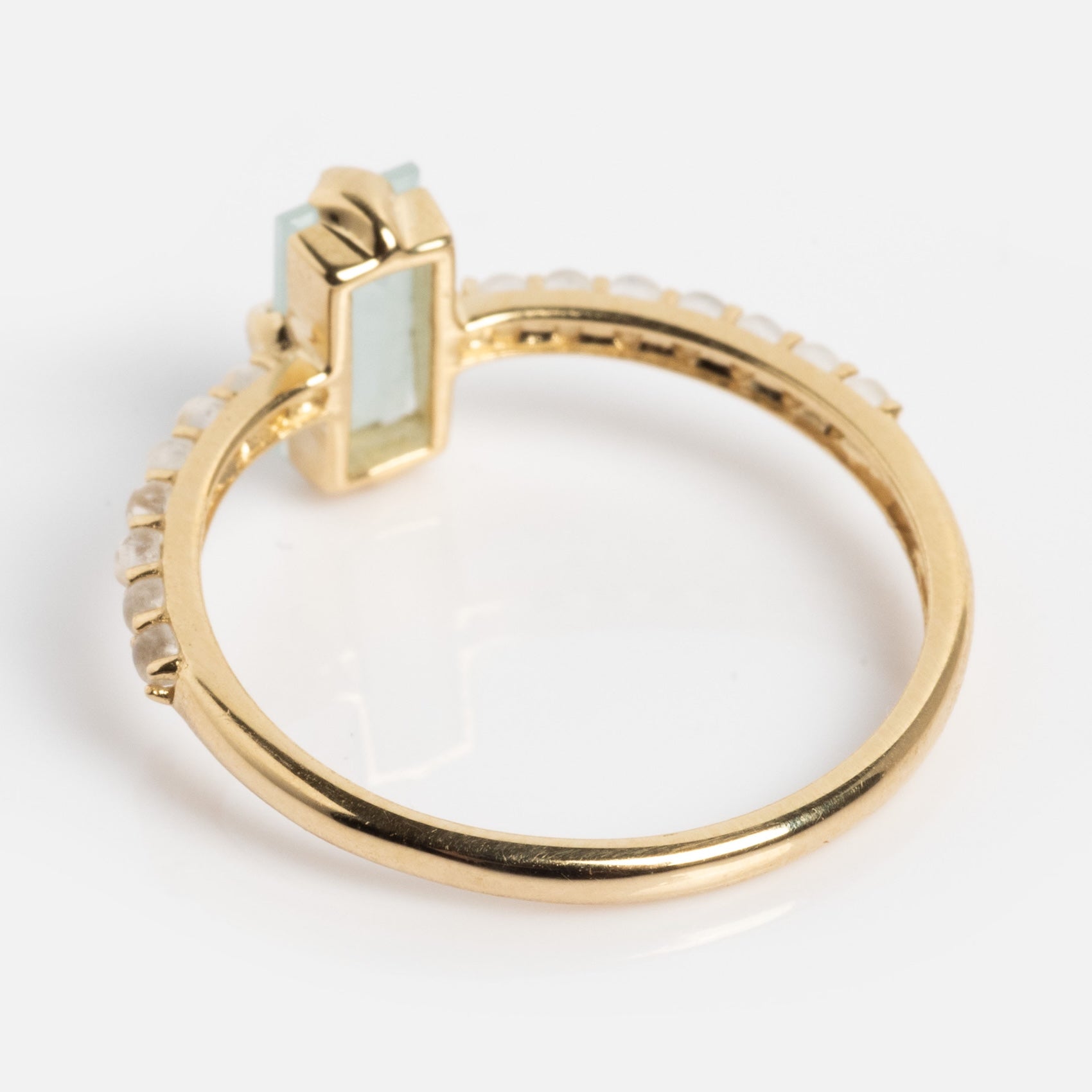The Solid Gold 2026 March Capsule Delicate Aquamarine Solitaire Ring features a rectangular aquamarine centerpiece and a row of small round stones on the band, showcased against a white background.