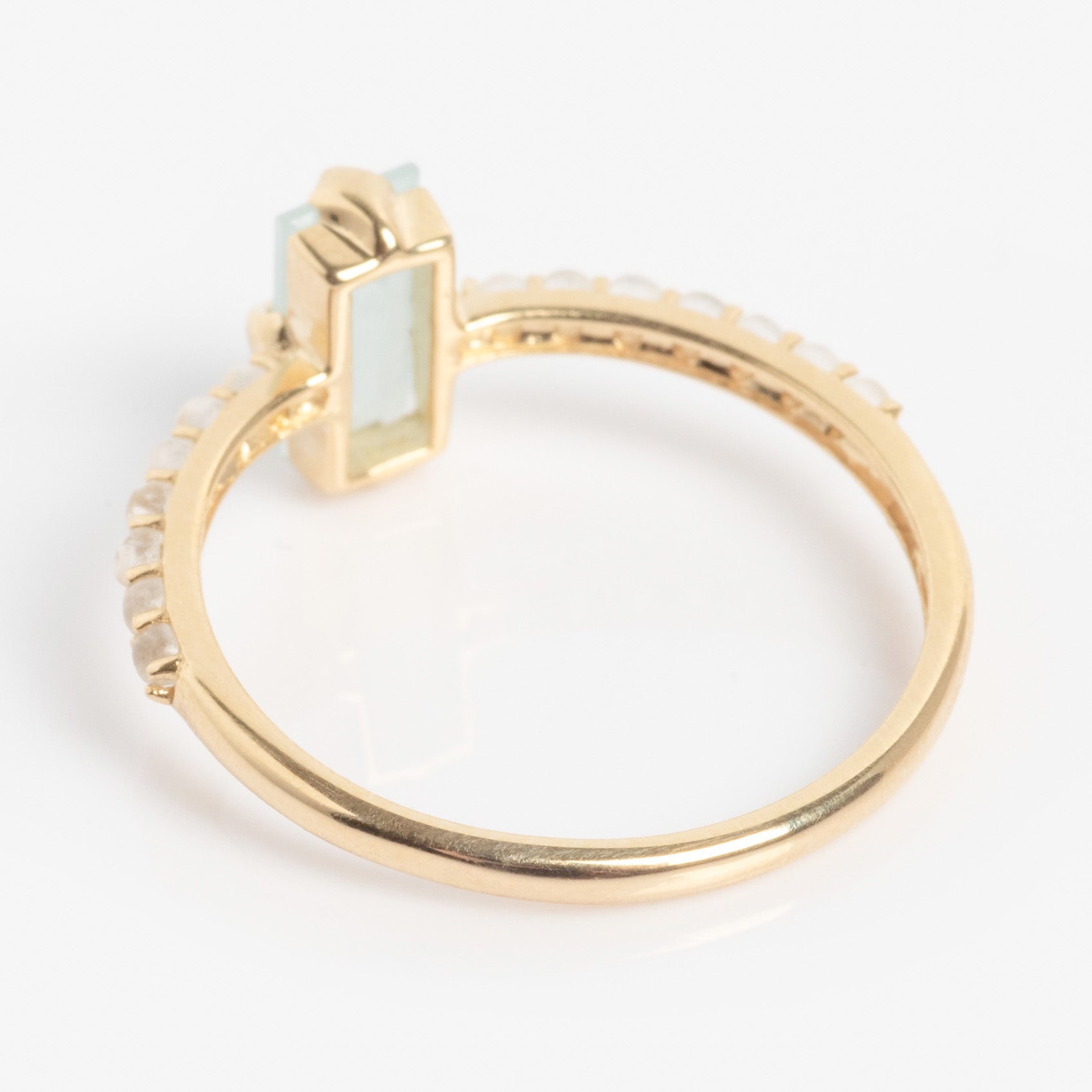 The Solid Gold 2026 March Capsule Delicate Aquamarine Solitaire Ring showcases a rectangular light blue aquamarine centerpiece and small round white stones on the band, elegantly displayed on a white background.