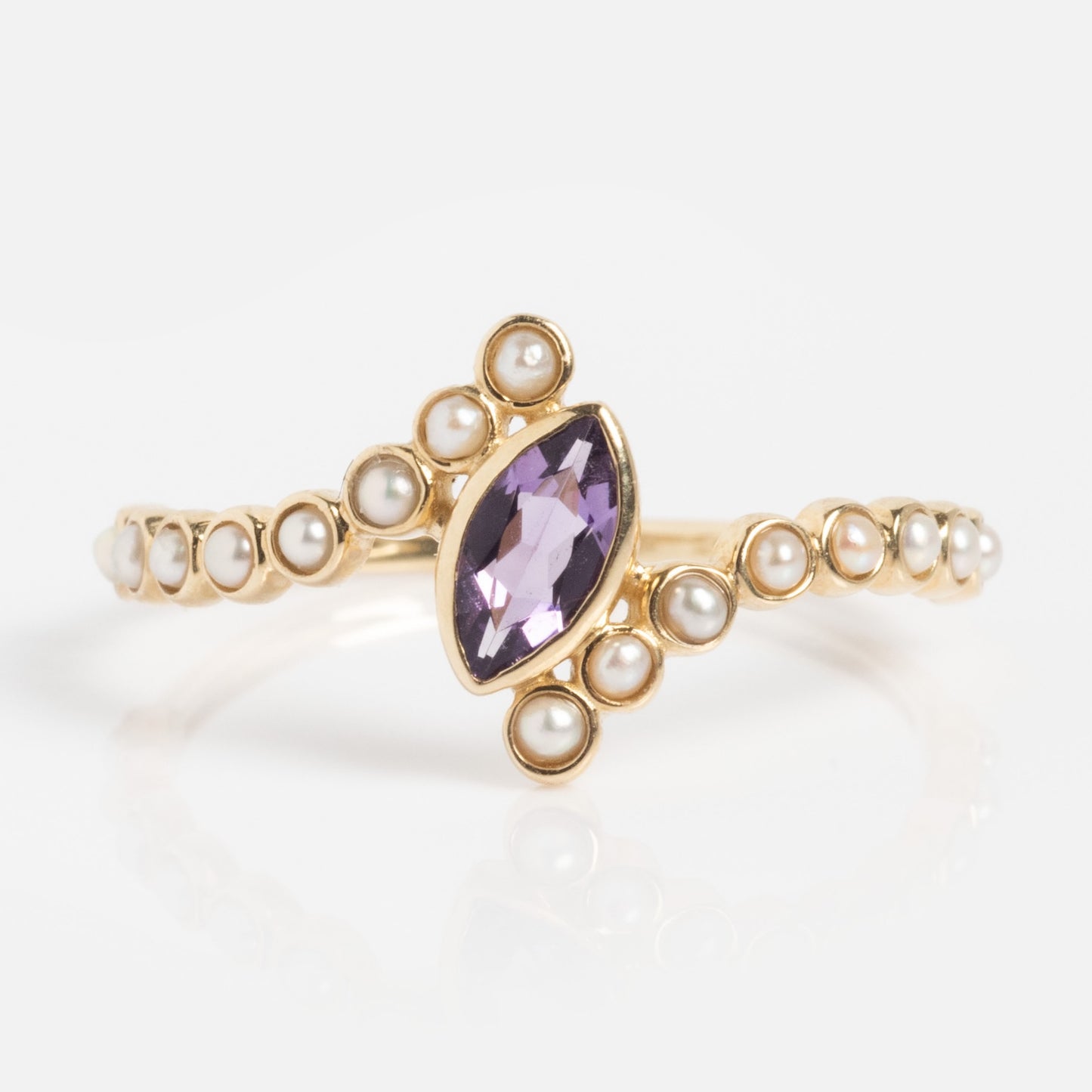 The Solid Gold 2026 February Capsule Floating Amethyst and Pearl Twist Ring features a marquise-cut amethyst center and round pearls accenting the band and main stone, displayed on a white background.