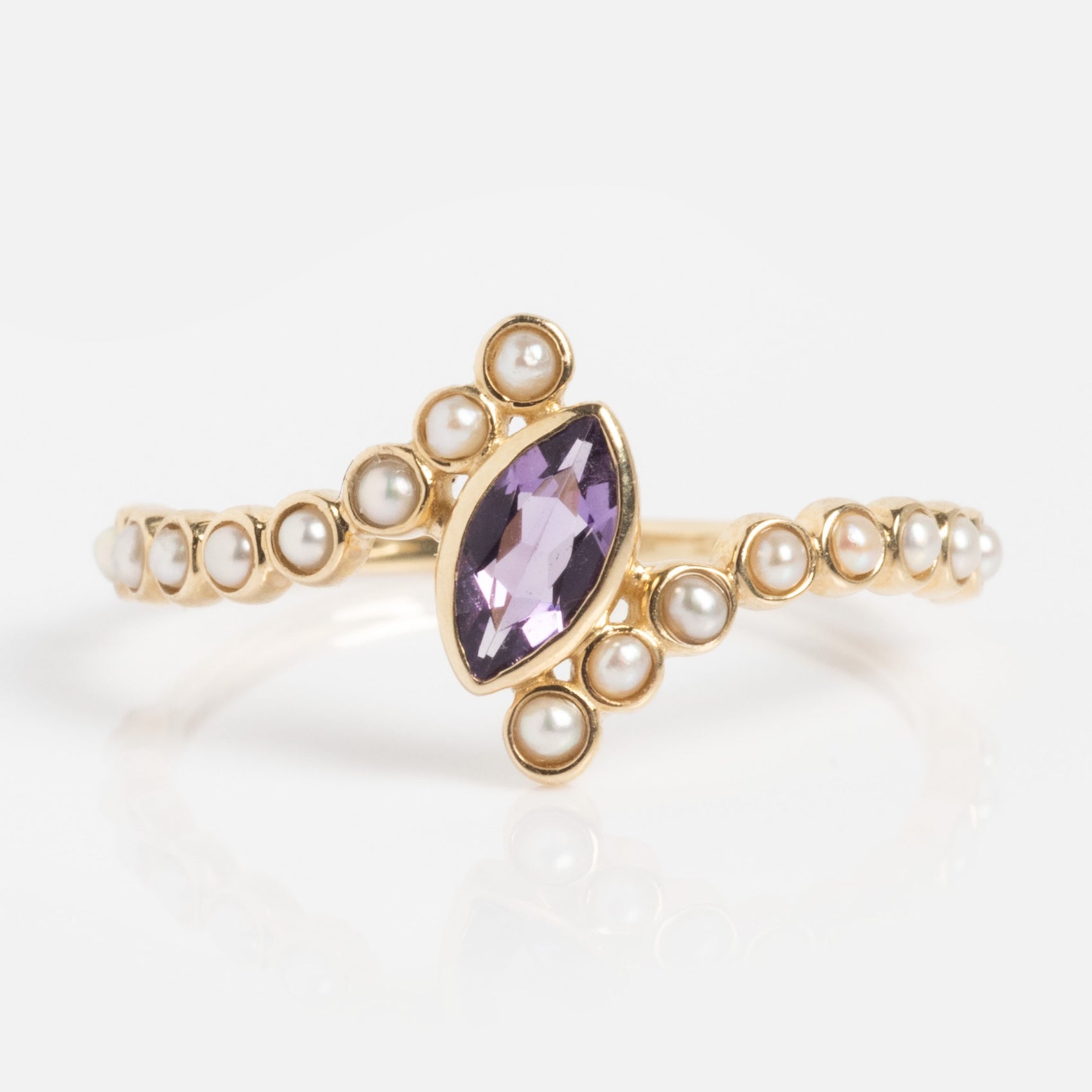 The Solid Gold 2026 February Capsule Floating Amethyst and Pearl Twist Ring features a marquise-cut amethyst center and round pearls accenting the band and main stone, displayed on a white background.