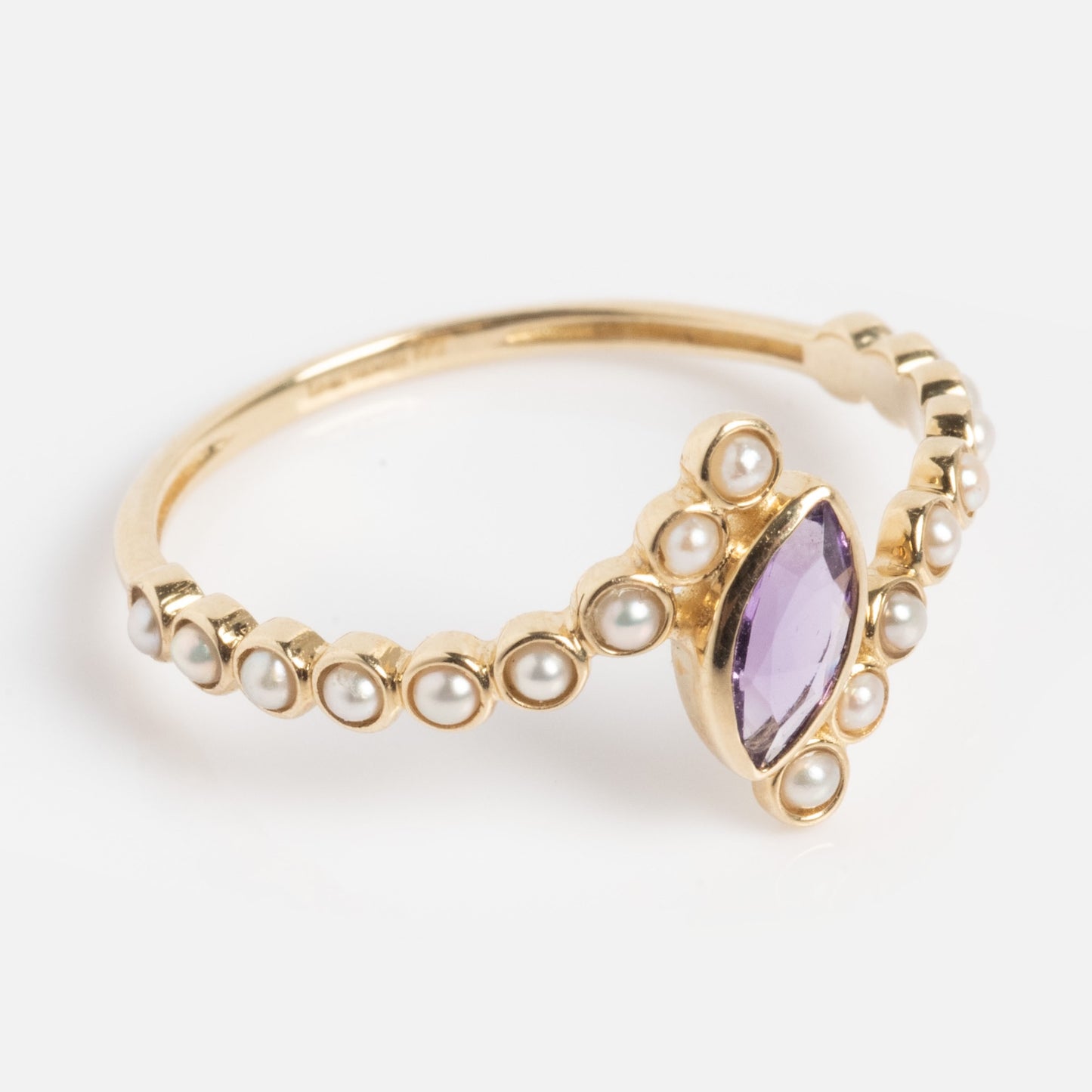 The Solid Gold 2026 February Capsule Floating Amethyst and Pearl Twist Ring features a marquise-cut amethyst centerpiece accented by small pearls along the band, shown against a white background.