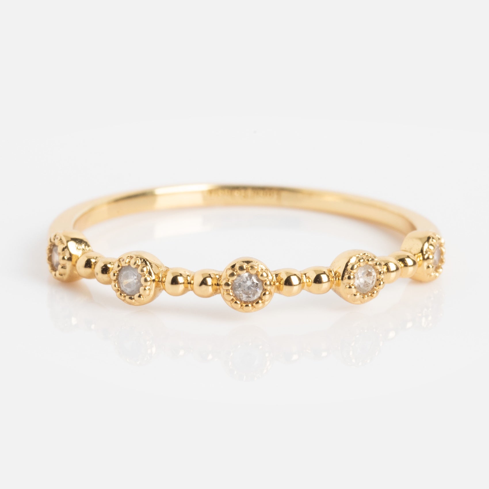 The Bezeled Beauty Stacking Ring is a delicate gold band with small round diamonds in raised, beaded circular settings, shown on a white background.