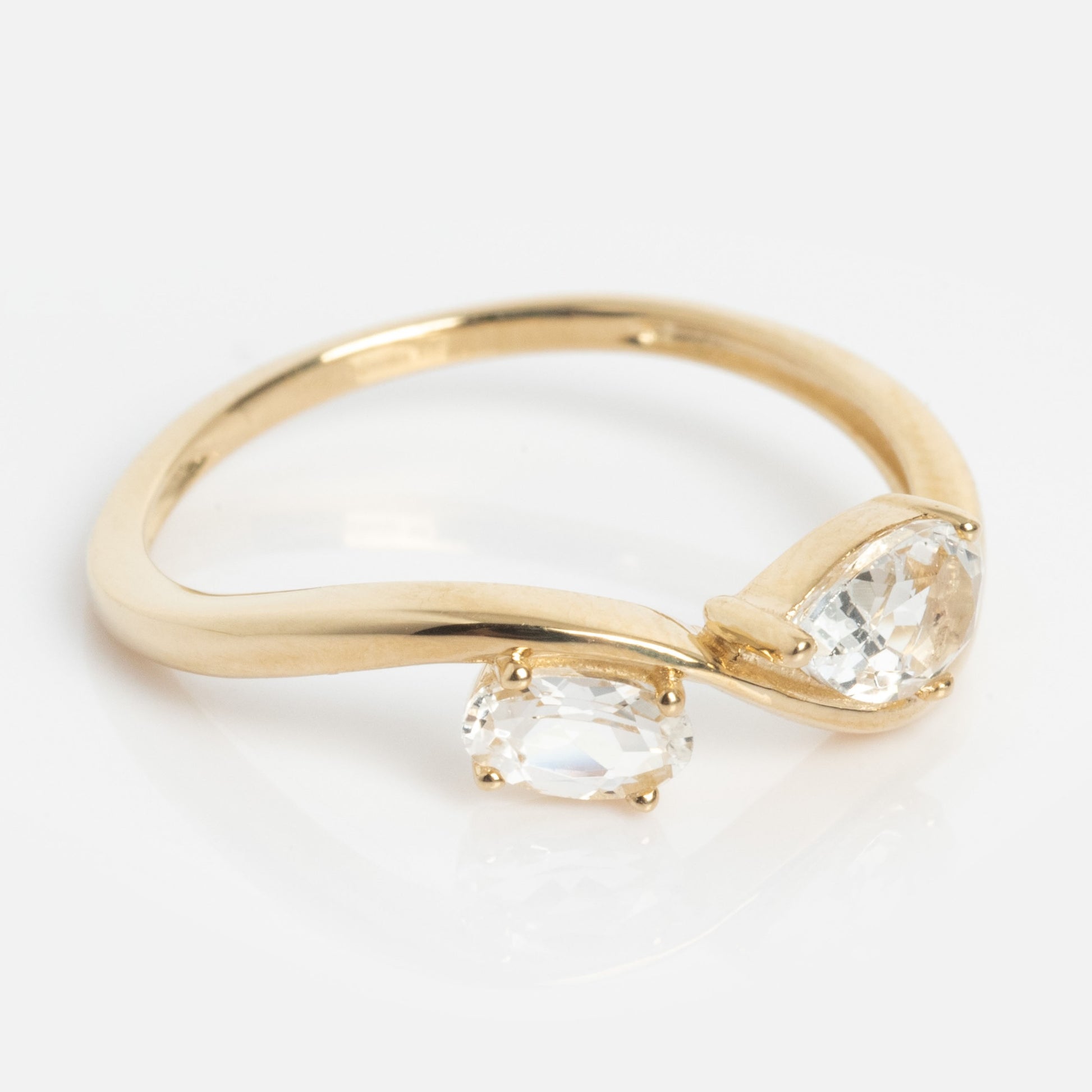 The Solid Gold 2026 April Capsule Floating Duo White Topaz Ring is a limited edition piece, featuring two clear white topaz stones set asymmetrically on a smooth, curved band, displayed against a white background.