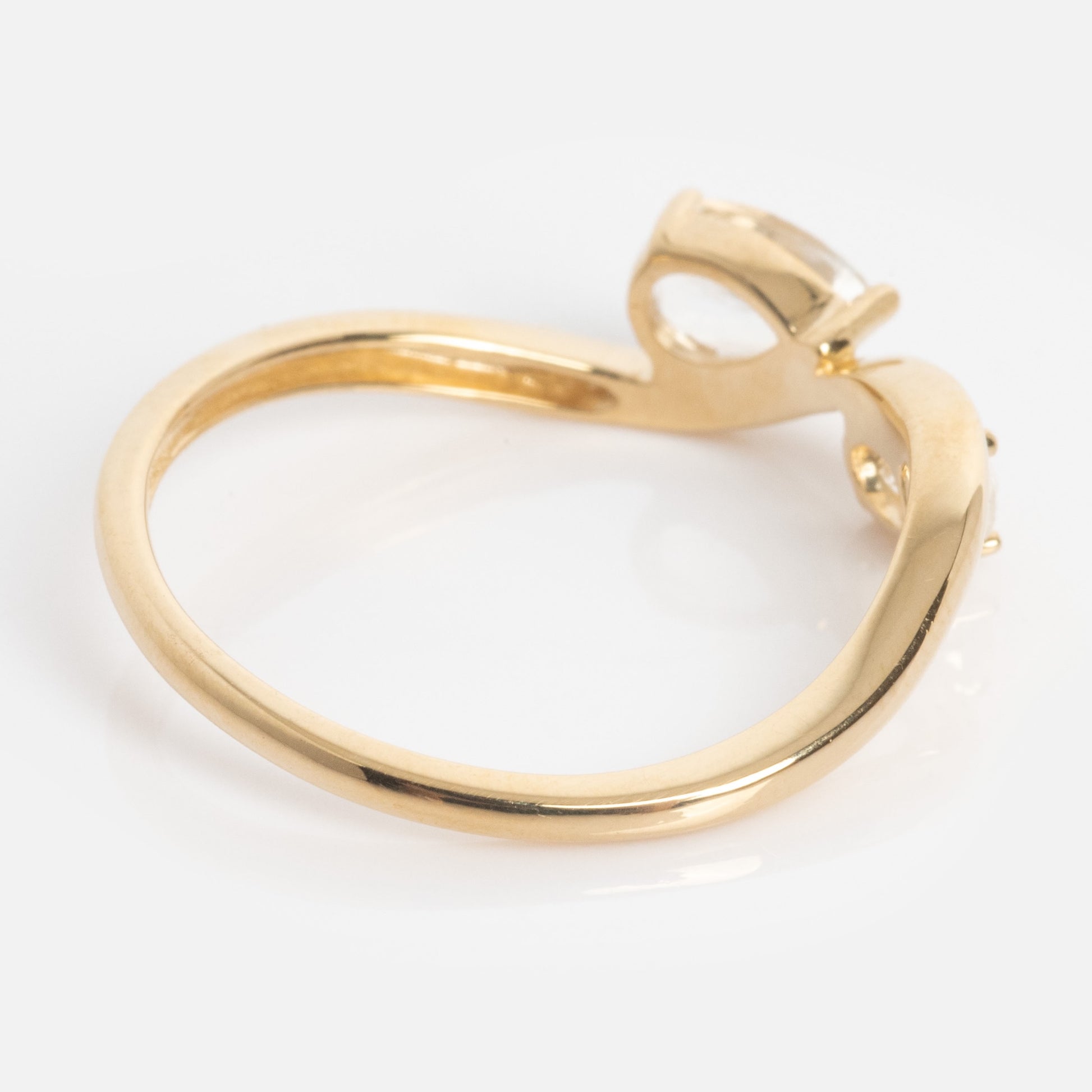 The Solid Gold 2026 April Capsule Floating Duo White Topaz Ring features a slender, slightly twisted gold band and a solitaire setting with a clear white topaz gemstone, displayed from the side on a white background.