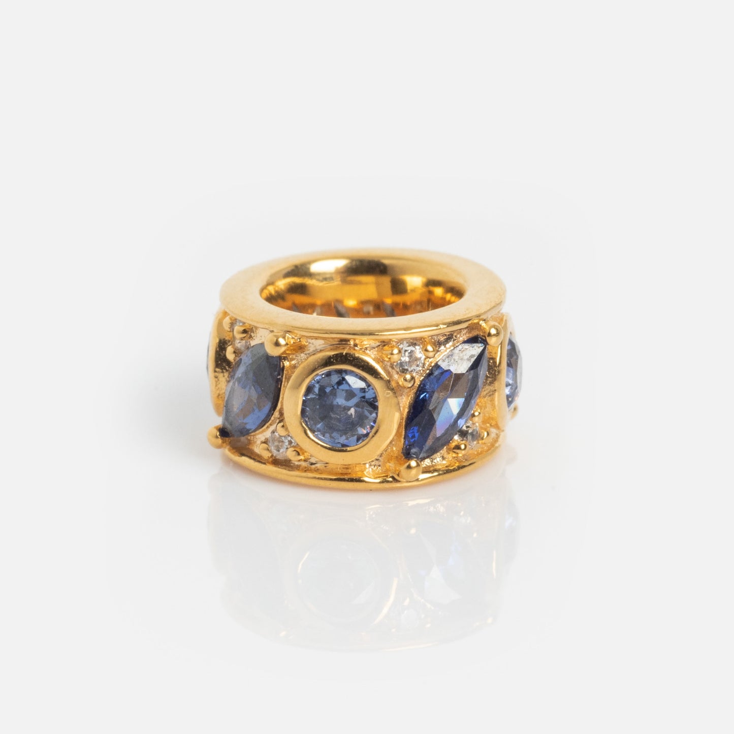 The Shades of You Birthstone Spacer Charm features round and marquise-cut blue gemstones arranged in a circular pattern, shown on a white background with a subtle reflection.