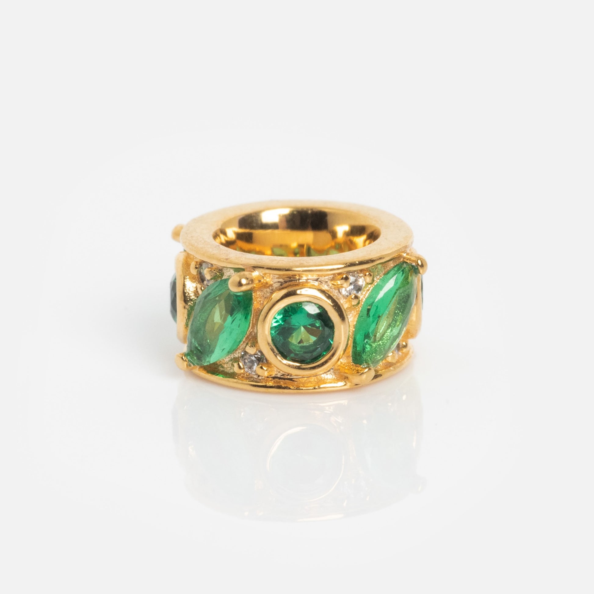The Shades of You Birthstone Spacer Charm features oval and round green gemstones with small clear stones on a wide, reflective gold band, set against a plain white background.