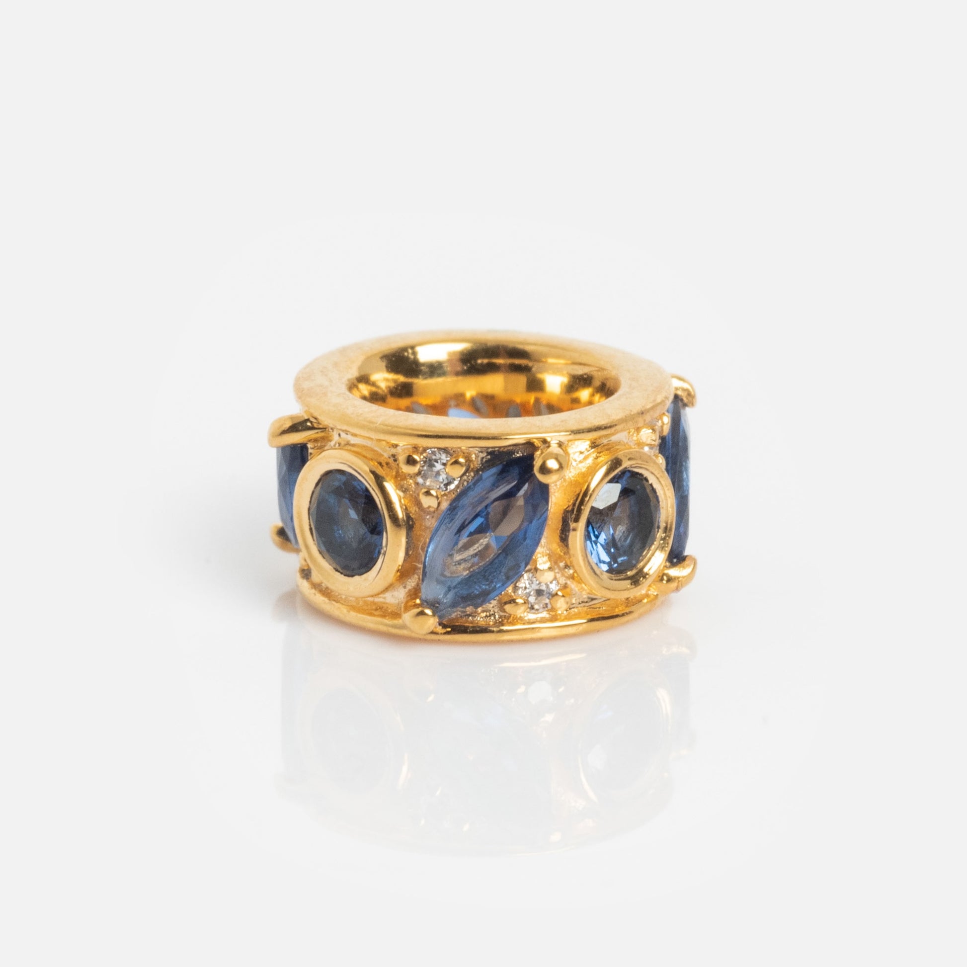The Shades of You Birthstone Spacer Charm features oval and marquise-shaped blue gemstones with small round clear stones in an intricate setting, set on a wide band and shown on a white background.