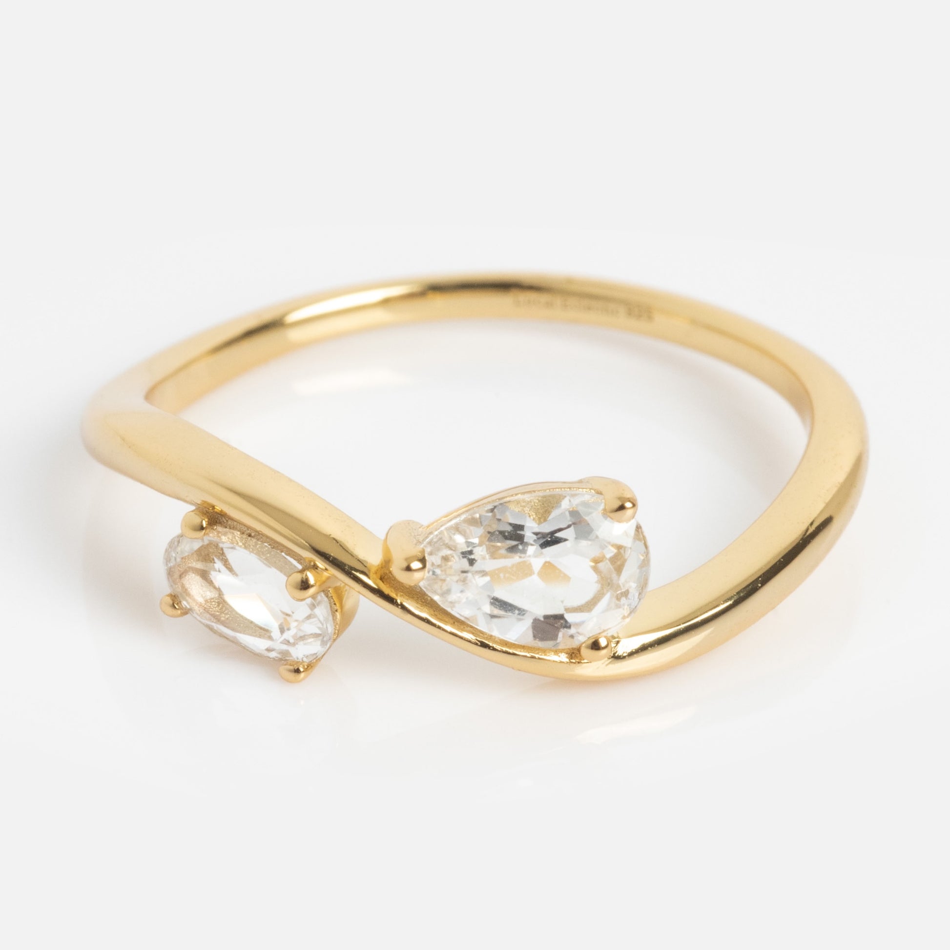 The 2026 April Capsule Floating Duo White Topaz Ring is a yellow gold vermeil ring with two pear-shaped white topaz gemstones set opposite each other in a bypass design. Ideal as an April birthstone piece or an elegant white topaz ring. Displayed on a white background.
