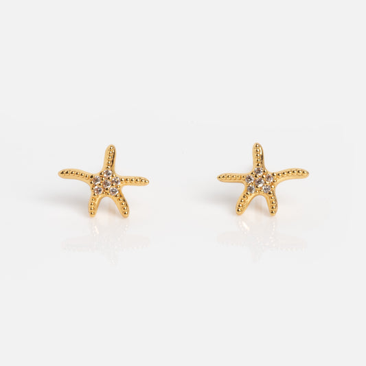 The Shimmering Starfish Studs are gold, starfish-shaped earrings featuring small clear stones, shown on a plain white background.