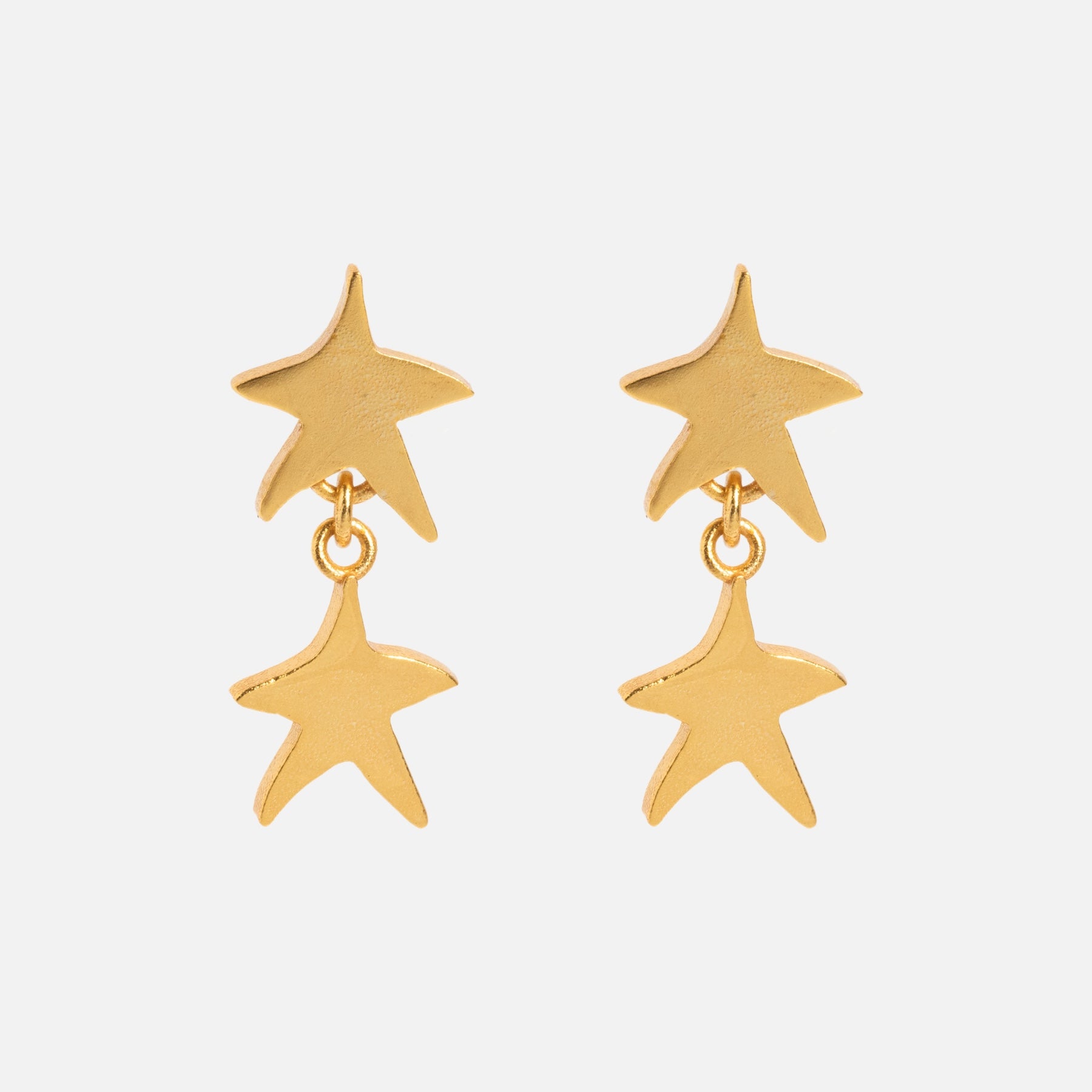 The Star Drop Earrings feature two gold star-shaped charms on each earring, with one star dangling beneath the other, shown against a plain white background.