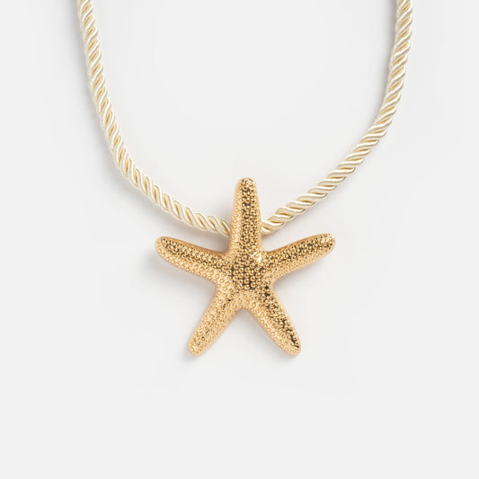 The Starfish Statement Pendant Necklace features a gold starfish pendant on a twisted gold chain, shown against a white background.