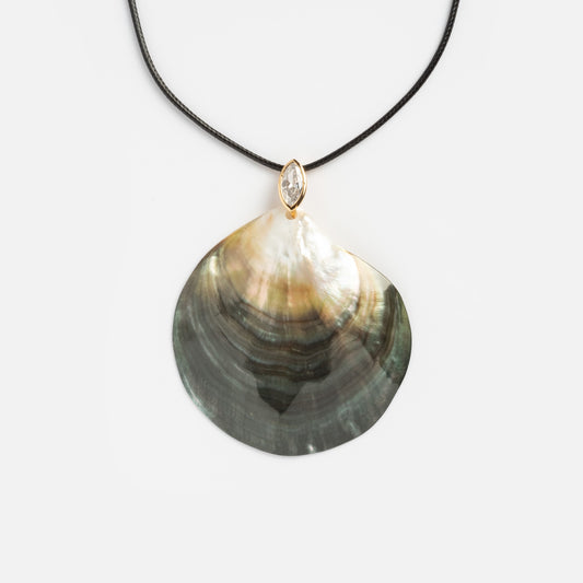 The Statement Shell Cord Necklace features a black cord with a large, iridescent shell pendant in green, gold, and cream tones, accented by a marquise-shaped crystal above the shell.