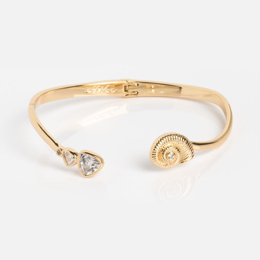 The Golden Nautilus Shell Cuff is a gold open bracelet with two clear gemstone accents on one end and a textured nautilus shell design on the other, shown against a plain white background.