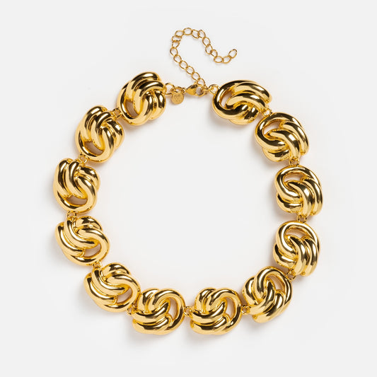 The Miami Necklace is an 18k gold plated chunky necklace with large, interlocking knot-shaped links and an adjustable chain clasp, adding bold elegance to any look. Displayed on a white background.