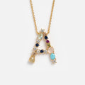 The Colorful Monogram Pendant is a gold necklace with an A-shaped pendant adorned with multicolored cubic zirconia and crystals, displayed on a white background.
