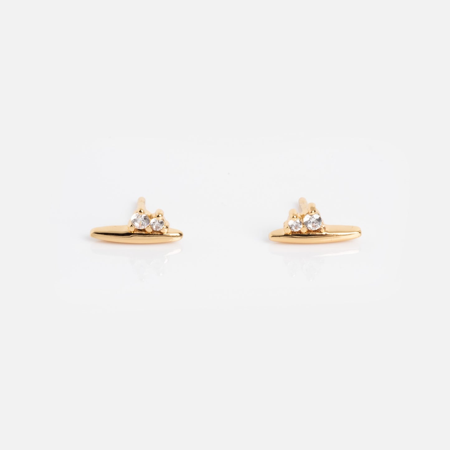 The Ida Bar Studs are small gold earrings featuring a horizontal bar with three round clear gemstones above it, shown on a plain white background.