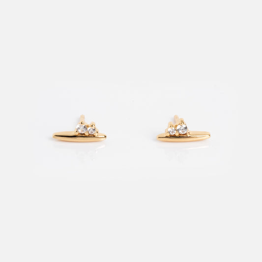 The Ida Bar Studs are small gold earrings featuring a horizontal bar with three round clear gemstones above it, shown on a plain white background.