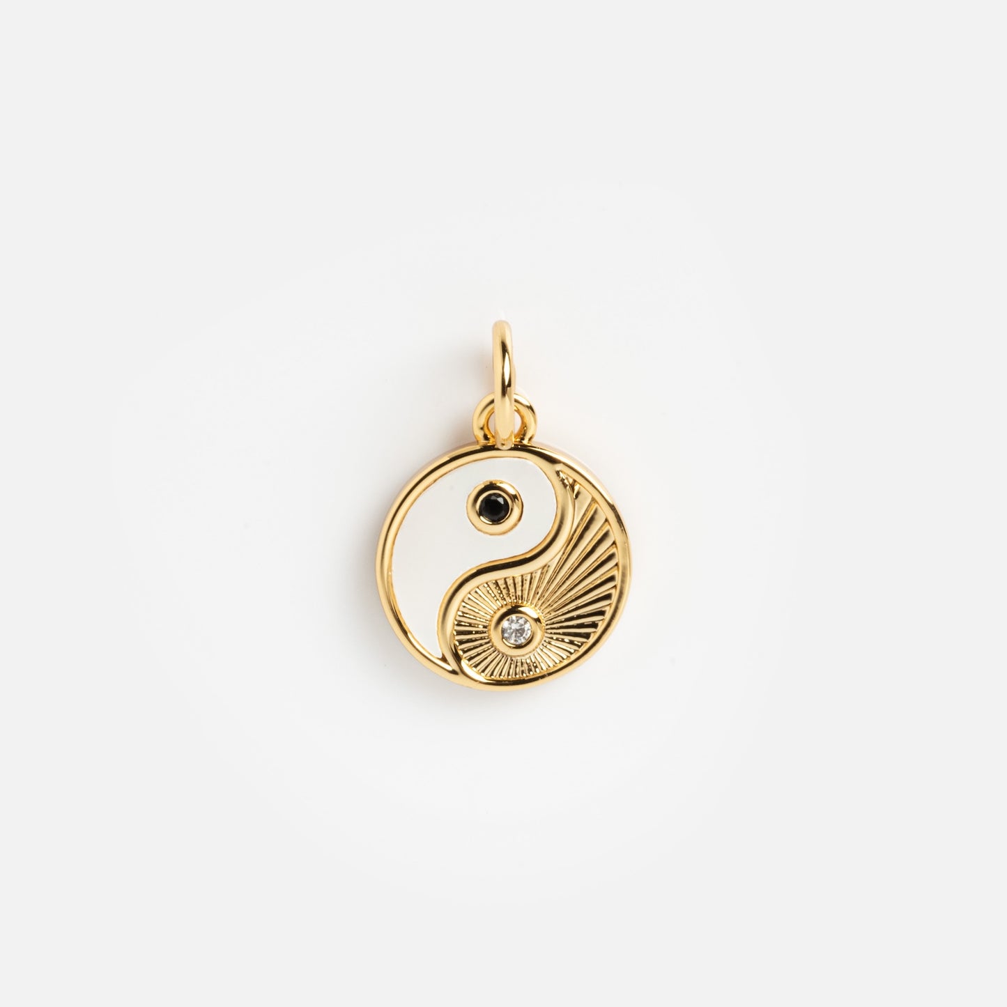 Charms by Mod + Jo features a gold yin-yang pendant with a white inlay, black stone, and sunburst design accented with a clear stone—an ideal stylish good luck charm.