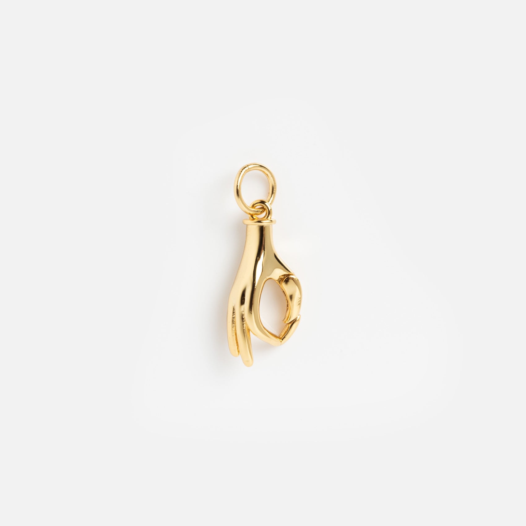 The Charms by Mod + Jo features a gold plated hand making an OK gesture, suspended from a small circular loop—a modern good luck charm shown on a plain white background.