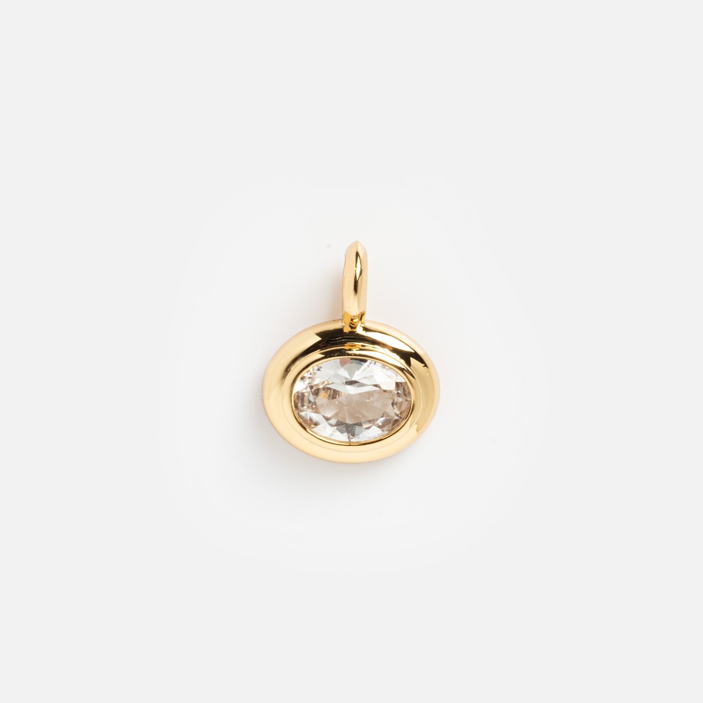 The Charms by Mod + Jo gold pendant features an oval clear gemstone at the center, symbolizing good luck. Photographed against a white background, this elegant piece adds a touch of charm to any look.