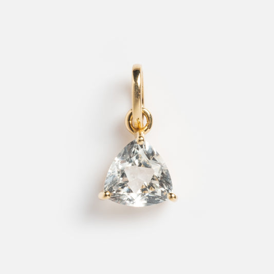 The Solid Gold Trillion Birthstone Charm is a 9k yellow gold pendant with a trillion cut birthstone set in three prongs, shown on a plain white background.