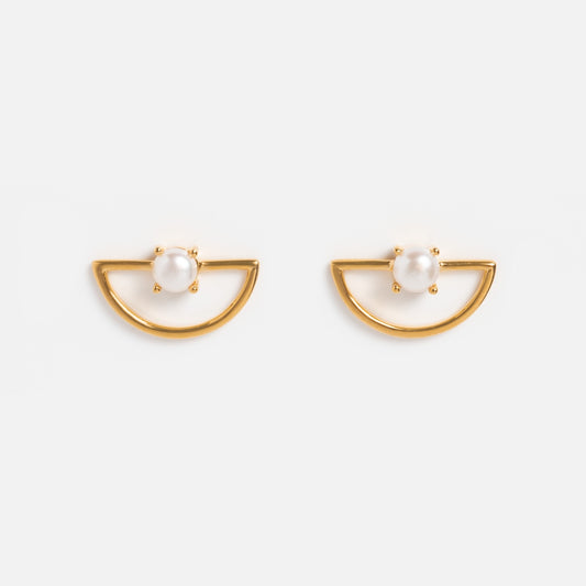 The Pine Earrings are 14k gold plated half-moon studs, each adorned with a single round freshwater pearl set at the top center, displayed against a plain white background.