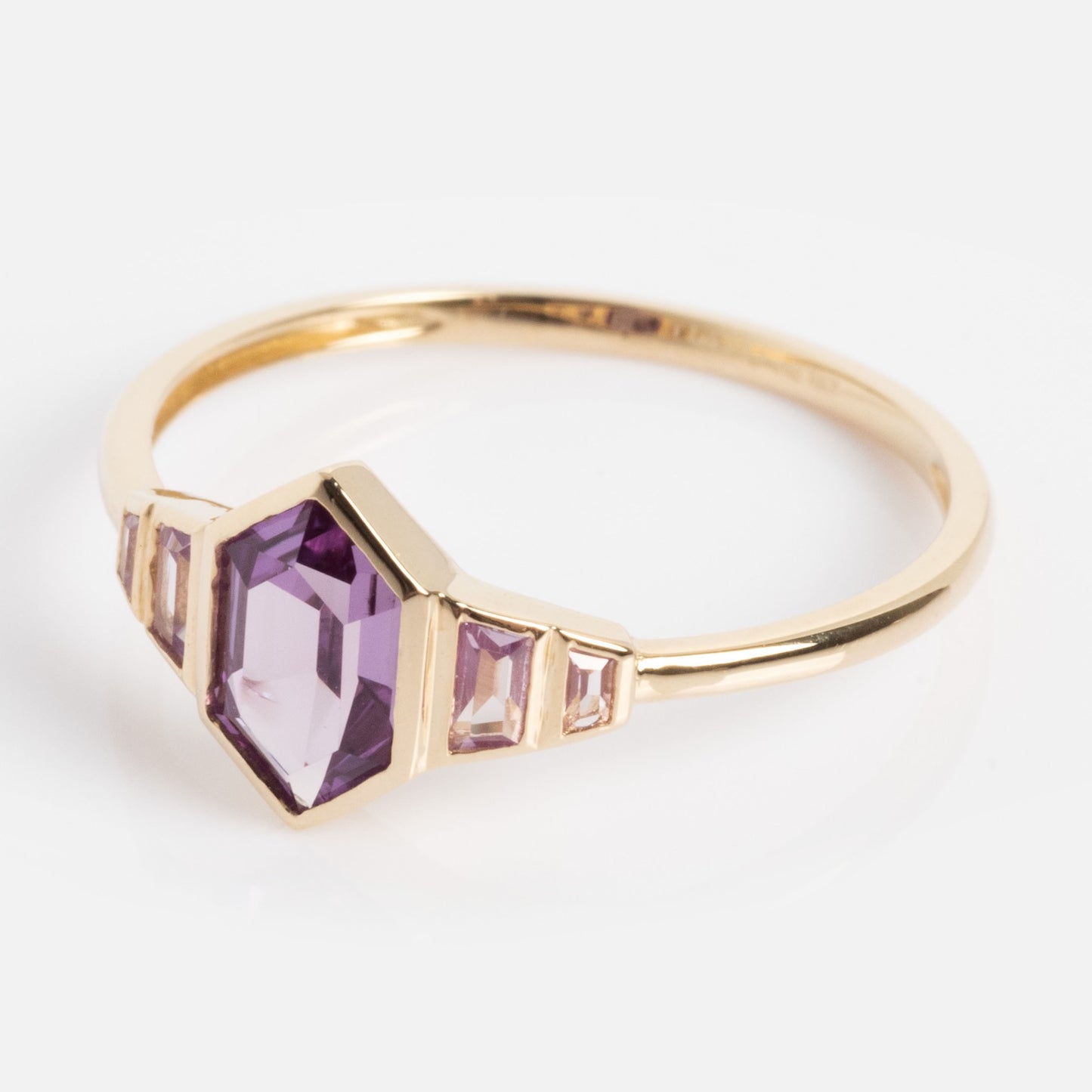 The Solid Gold 2026 June Capsule Art Deco Alexandrite Ring features a central hexagonal purple stone with two small rectangular purple stones on each side, displayed on a plain white background.