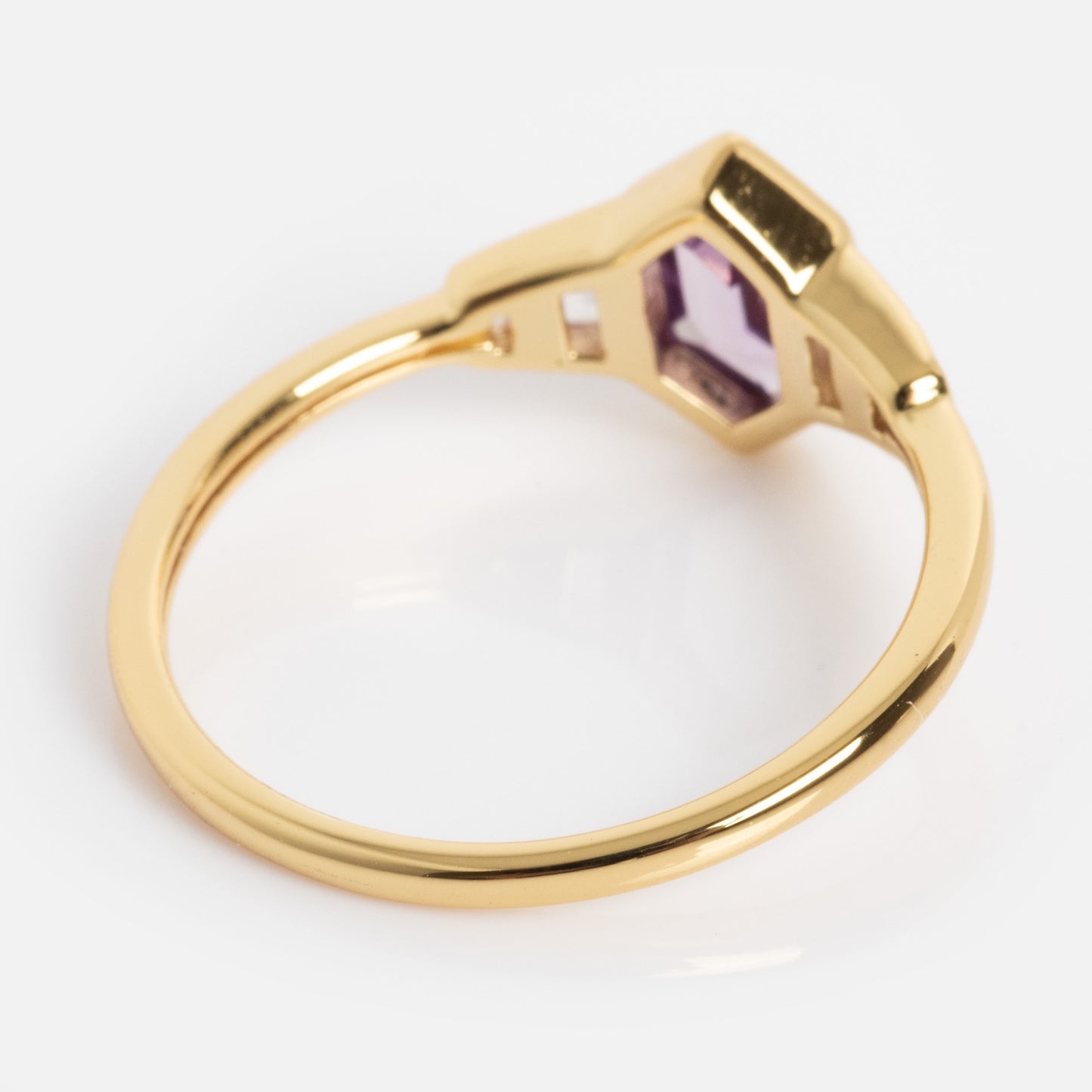The 2026 June Capsule Art Deco Alexandrite Ring features a thin gold band and a hexagonal purple gemstone set in a raised bezel, shown from an angled overhead view on a white background.