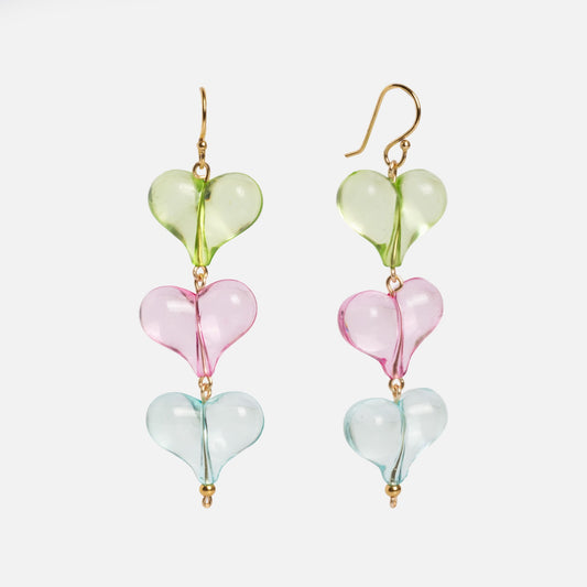 Glossy Hearts Earrings: A pair of dangle earrings with three stacked glass heart beads in green, pink, and blue. Gold hooks and accents complete the look. Shown on a white background.