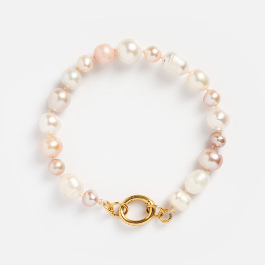The Beaded Gemstone Charm Holder Bracelet features round, multicolored pearls in white, cream, and light pink with a gold lobster clasp, displayed on a plain white background.