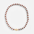 The Beaded Gemstone Charm Holder Necklace features alternating red and white oval beads with a gold lobster clasp, elegantly arranged in a circle on a white background—ideal for gemstone statement jewelry lovers.