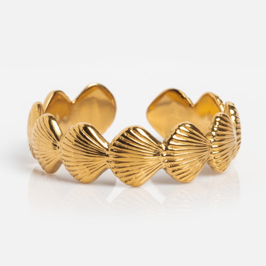The Seashells Ring by Jackie Mack Designs features an open, adjustable gold band with a repeating pattern of textured, fan-shaped shells around its circumference, shown on a white background.