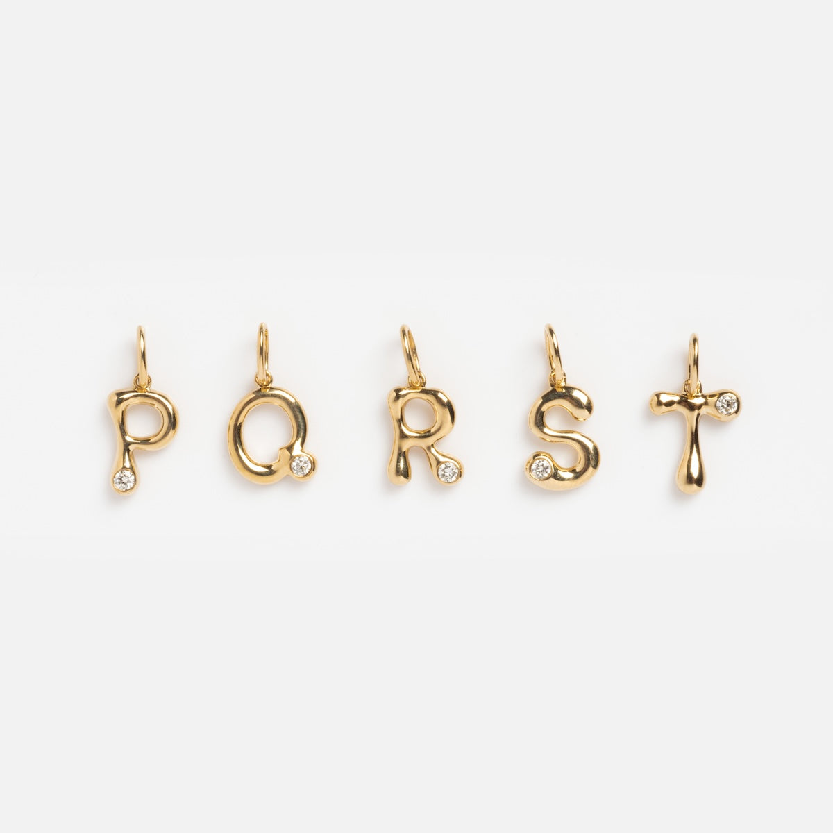Five Solid Gold Diamond Initial Charm Samples—letters P, Q, R, S, and T—each made from 9k yellow gold and set with a 2mm lab-created diamond, are arranged in a row against a plain white background.
