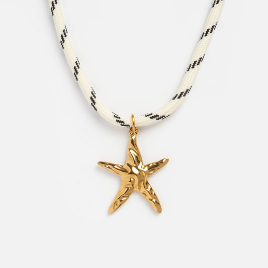 The Starfish Charm Paracord Necklace features a gold starfish pendant on thick white paracord with black diagonal stripes, shown against a plain white background—a bold nautical accessory.