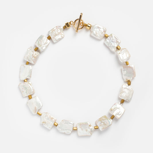 The Cool Girl Pearls Necklace showcases large, irregular square freshwater pearls separated by small gold cylindrical beads and finished with a gold toggle clasp, elegantly displayed on a plain white background.