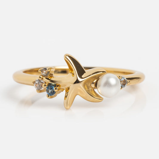 Gold starfish ring with embedded pearls and gemstones on a light background