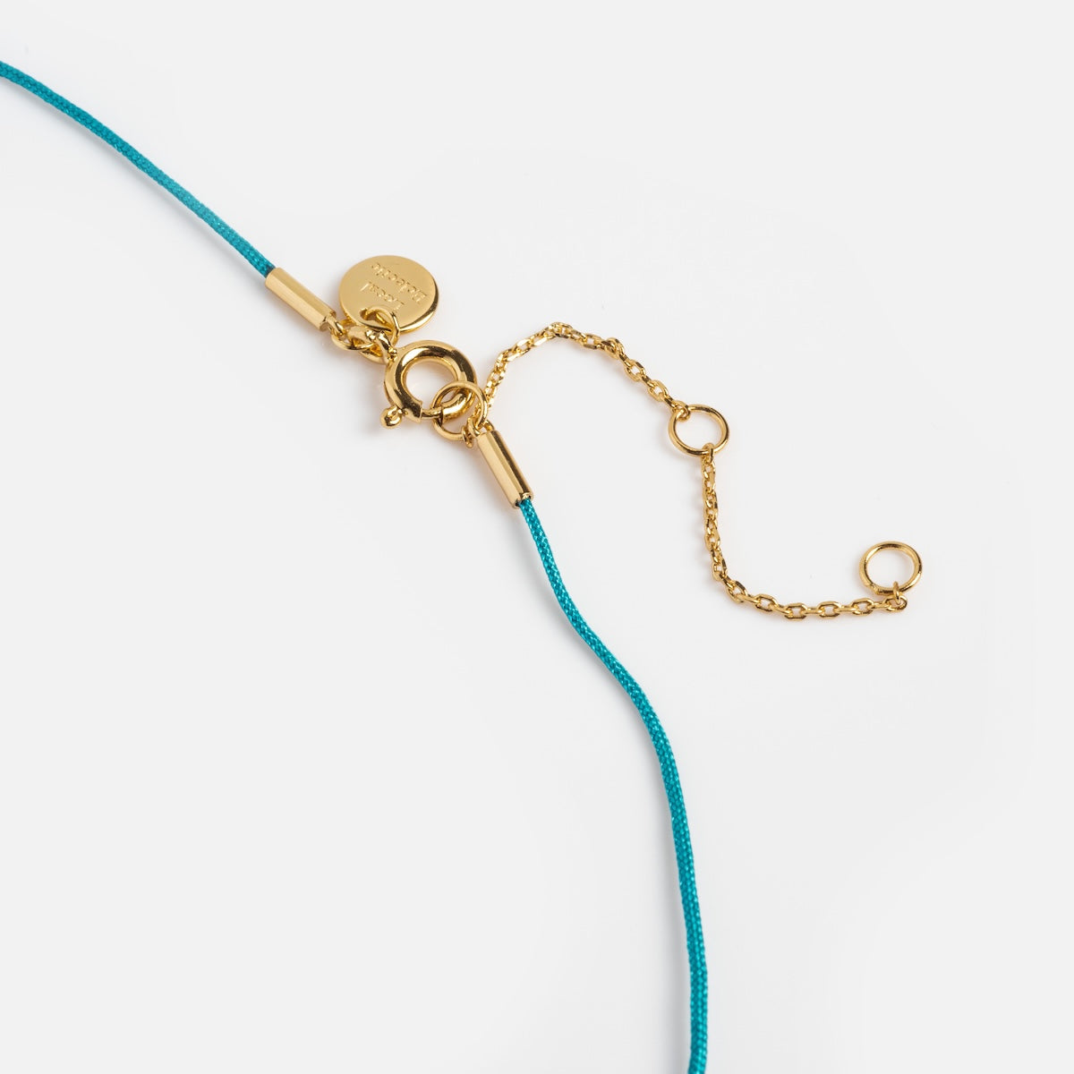 Gold clasp and turquoise cord on a white background