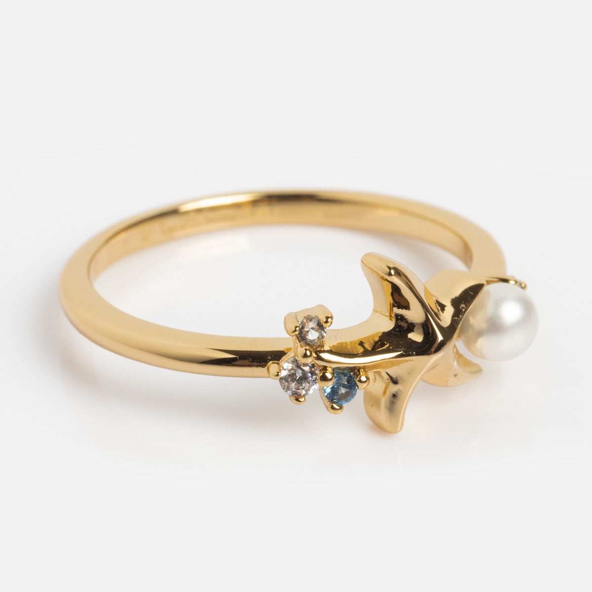 Gold ring with a bird design and embedded stones on a white background