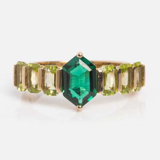 The 14k Emerald & Peridot Ring Sample Size 7 showcases a large emerald-cut lab-created emerald at the center with rectangular green peridots on each side, all set in solid yellow gold against a white background.