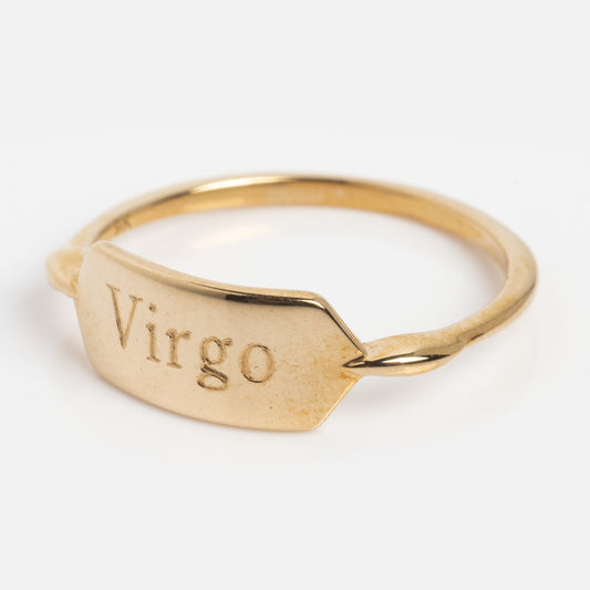 A Solid Gold Engraveable Bar Ring Virgo Sample Size 7 in 9k yellow gold features a flat, rectangular face engraved with Virgo, resembling a delicate gold bar, shown against a plain white background.