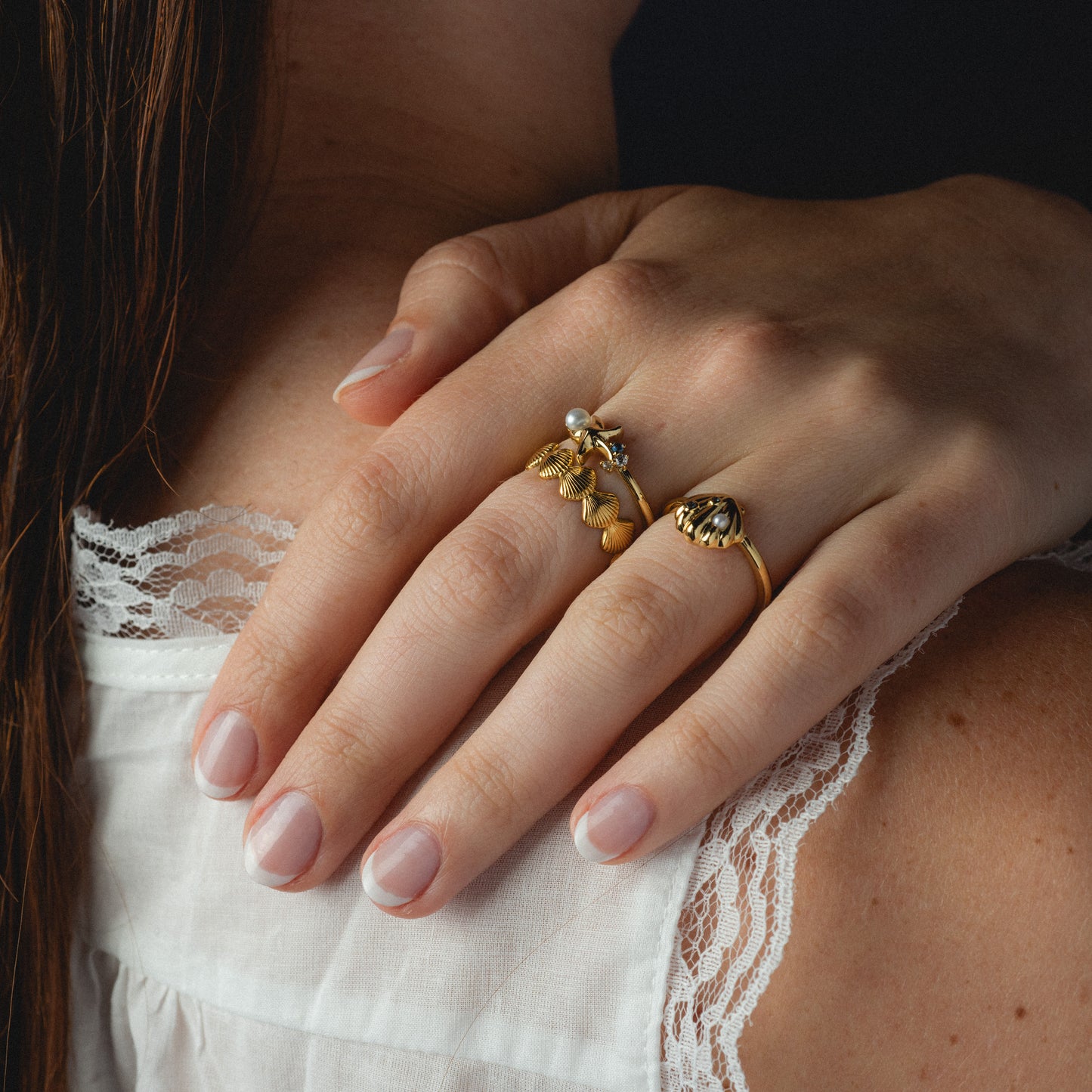 Close-up of a hand wearing gold rings on a white lace garment