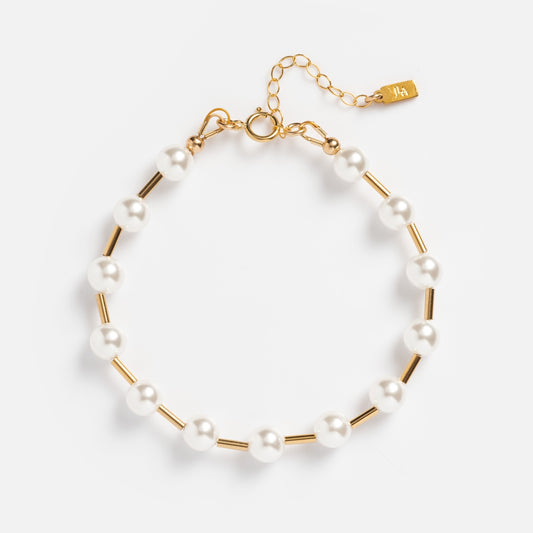 Introducing the Gal Pearl Bracelet: featuring a delicate dot-and-dash design with alternating white pearls and gold-filled tube beads, finished with a gold adjustable chain and clasp. Shown on a white background.